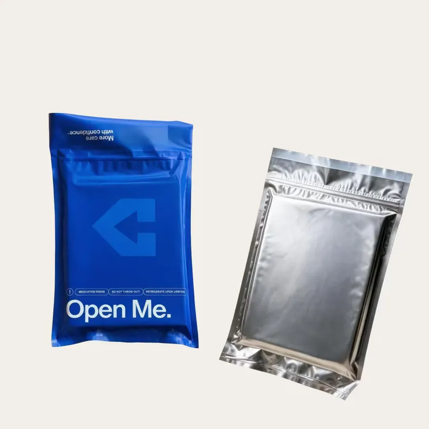 A blue mailer printed "Open Me." beside a foil-lined metallic mailer.