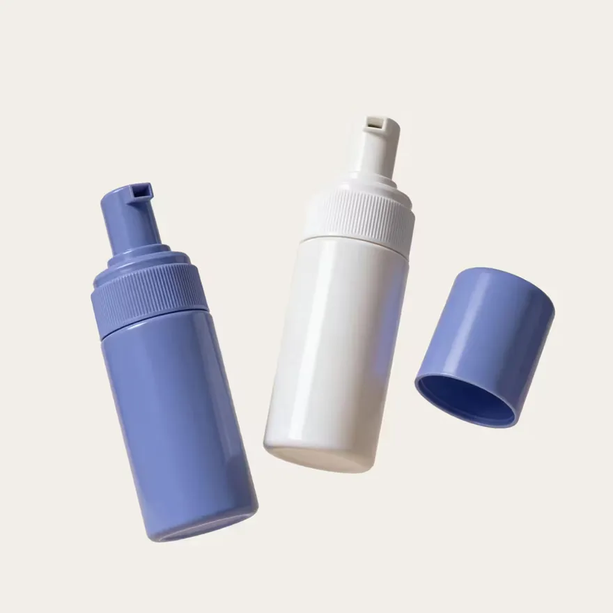 A lavender spray bottle and a white fine-mist bottle with its cap alongside.