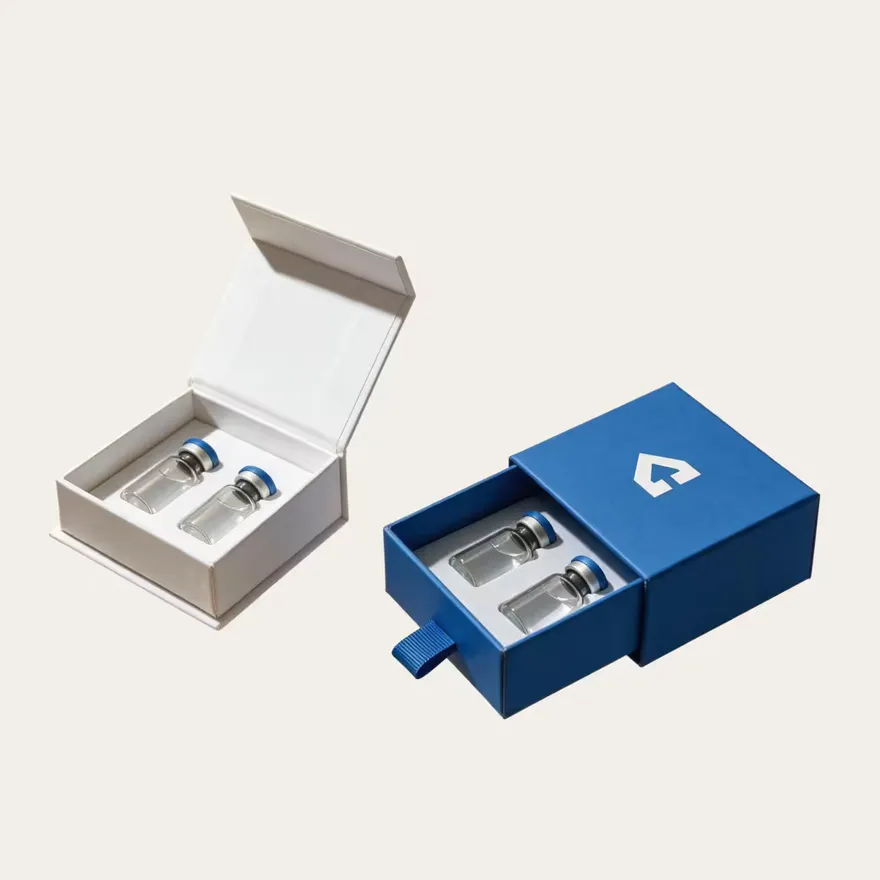A white magnetic-closure box and a blue drawer box, each holding two vials.